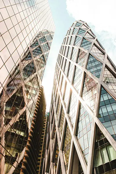 Advanced Web Development from a specialized web design agency Low-angle view of a glass skyscraper reflecting the sky, symbolizing scalable code and enterprise-grade web development.